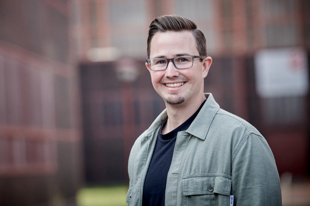 Porträt Rehalehrer lächelt vor Backsteinwand am Welterbe Zeche Zollverein.