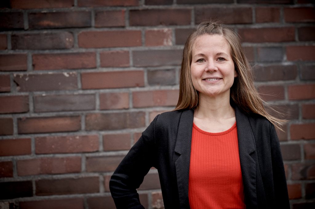 Porträt von Rehalehrerin lächelt vor Backsteinwand am Welterbe Zeche Zollverein.